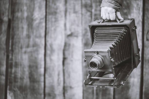 Large format retro camera, 5x7 inches. Photographer holds in hand old studio camera. Monochrome effect, copyspace. Concept - photography of the 1930s-1950s