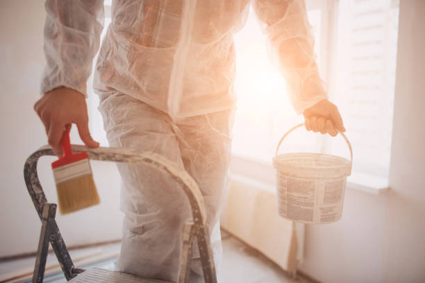 istock The builder works at the construction site and measures the ceiling. Worker with bucket and paint roller near wall 1137732517