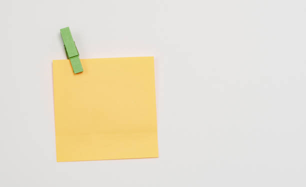 istock Orange paper notes fastened with a wooden clothespin on a white background. 1137734311