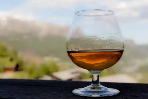 Photo of Glass with cognac, whiskey or brandy in front of idyllic landscape