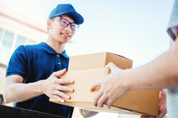 delivery concept asian man hand accepting a delivery boxes from professional deliveryman at home - postal worker truck driver delivering delivery person imagens e fotografias de stock