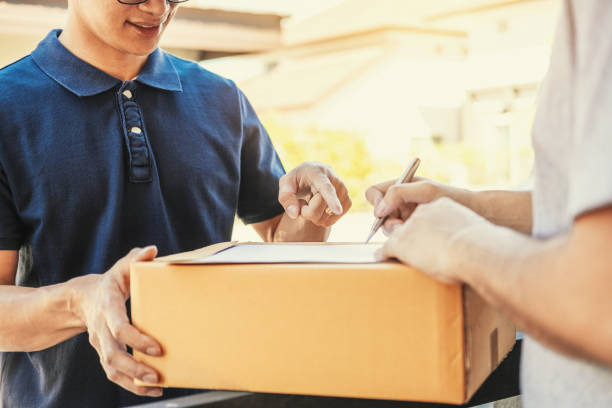 customer man signature in clipboard to receive package from professional delivery man at home - postal worker truck driver delivering delivery person imagens e fotografias de stock