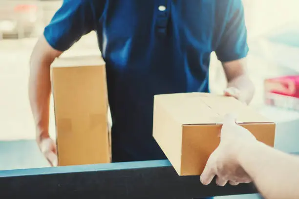 Delivery concept Asian Man hand accepting a delivery boxes from professional deliveryman at home
