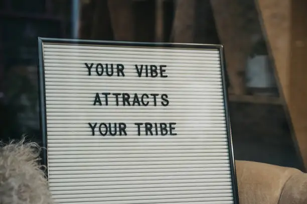 Your vibe attracts your tribe motivational quote on a white letter board.
