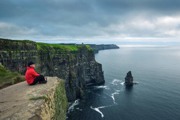 excursionista sentado en los acantilados de moher - cliffs of moher republic of ireland panoramic cliff fotografías e imágenes de stock