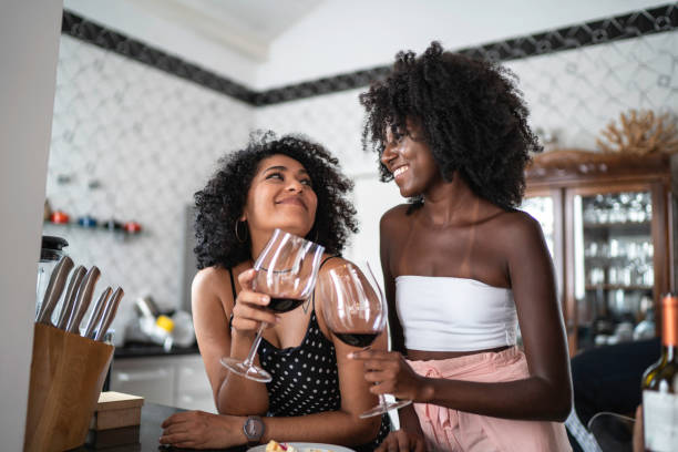 lesbische paar of vrienden drinken wijn in de keuken - drinking wine stockfoto's en -beelden