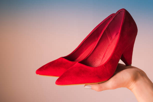 Woman holding red high heels on hand Woman holding red high heels on hand on blue and pink background. womens blue suede shoes stock pictures, royalty-free photos & images