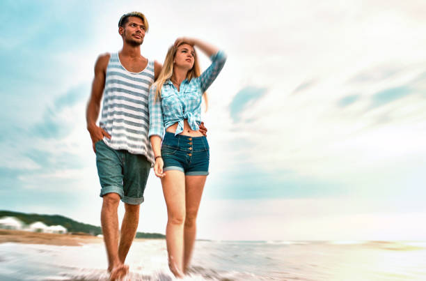 Young Couple walking along the beach at sunset. Motion blur creative post production