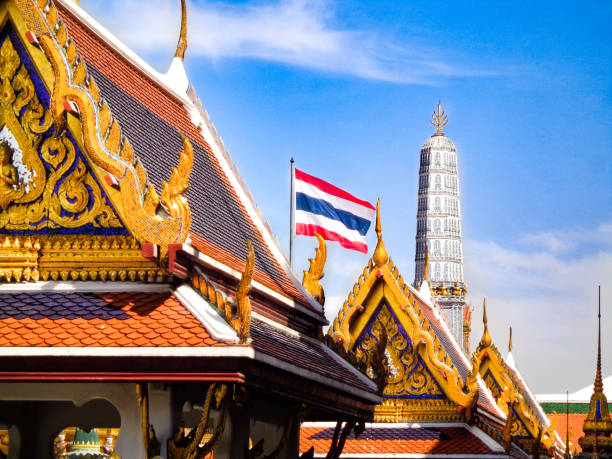 Thai Flag and Traditional Golden Buddhist Temples Grand Palace: Thai Temples, Golden Rooftops, and Thai Flag - Bangkok, Thailand thai flag stock pictures, royalty-free photos & images