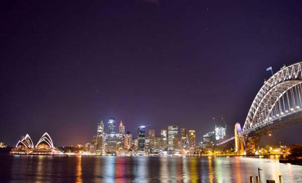 centro de sydney, porto de sydney, e ponte iluminada na noite (tiro largo da arquitectura da cidade) - sydney harbor panoramic sydney australia skyline - fotografias e filmes do acervo