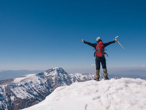 istock Climber is open arms  in the summit of high altitude mountain 1137756077