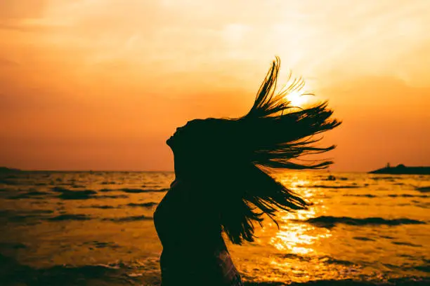 Photo of silhouette of young girl hair flick splash over summer sea sunset background. freedom fun concept.