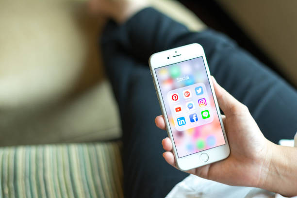 banguecoque, tailândia-janeiro 8, 2017: smartphone do iphone da terra arrendada da mulher de negócio com ícones de meios sociais na tela como o estilo de vida de relaxamento, tecnologia do internet no cotidiano - iphone google holding telephone - fotografias e filmes do acervo