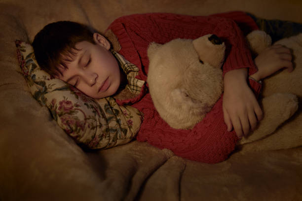istock boy sleep in bed with bear toy 1137761934