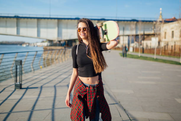 istock Young hipster woman with skateboard on her shoulder. 1137763021