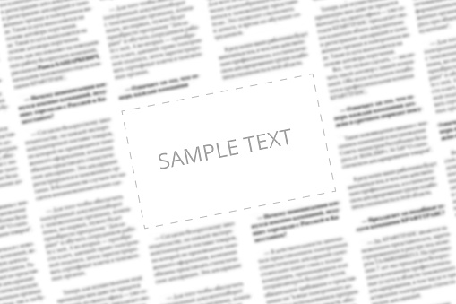 Angularly shot black and white newspaper with copy space in the middle. Written words Sample Text in the blank square on the blurred tabloid page background. Designer mockup for paper news page. Type