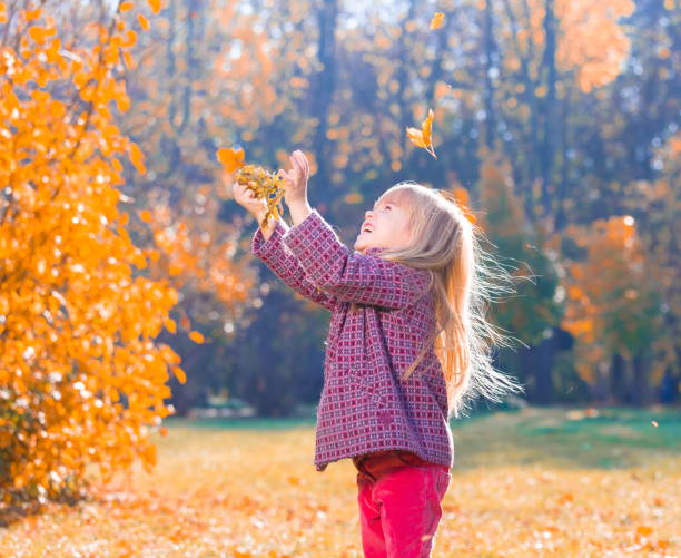 istock Girl, garden, autumn, falling leaves 1137763110