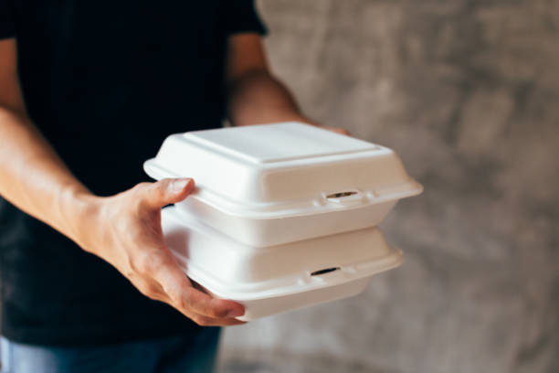 Close-up of delivery man handing a slack of foam lunch box Close-up of delivery man handing a slack of foam lunch box - Foam box is toxic plastic waste. It can be used for recycling and environment saving concept polystyrene box stock pictures, royalty-free photos & images