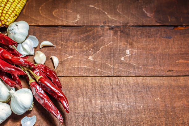 Red chili peppers, garlic and corn on a wooden background. Close-up view with space for text.