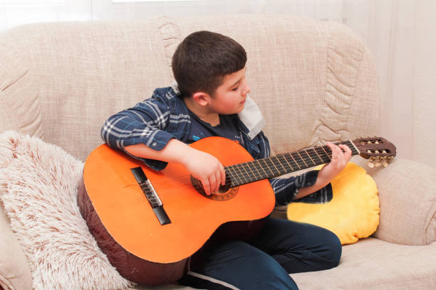 istock The boy is playing guitar at home 1137767133