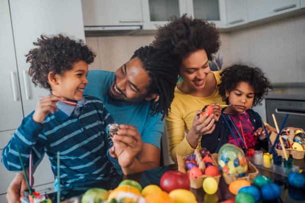улыбающаяся семья украшает пасхальные яйца - vacations two generation family holiday easter стоковые фото и изображения