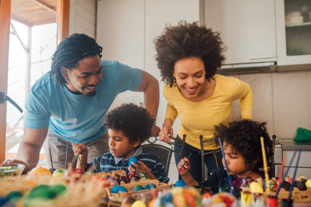 istock Parents smiling when looking at children decorating eggs 1137772036