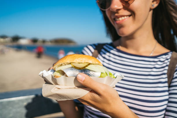 Fish sandwich at Travemünde Young tourist woman is eating fish sandwich at Lubeck Travemünde baltic sea people stock pictures, royalty-free photos & images