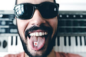 Musician With Synthesizer Showing LSD On His Tongue