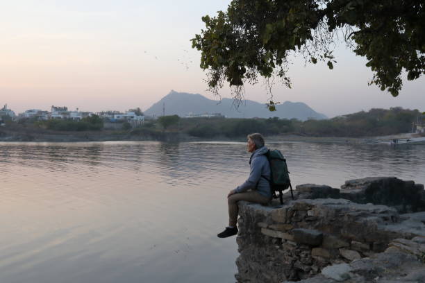 istock Hiker sits on rock above lake at sunset 1137780100