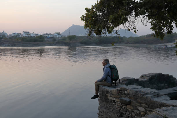 istock Hiker sits on rock above lake at sunset 1137780209