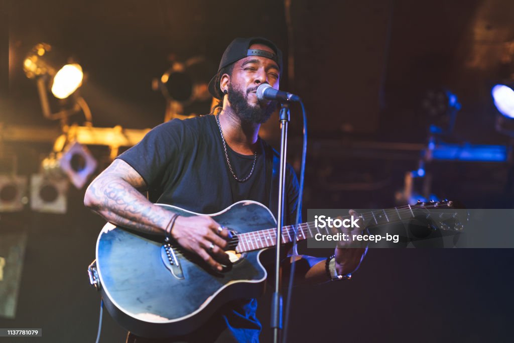 Zwarte man spelen akoestische gitaar en zingen op het podium - Royalty-free Zanger Stockfoto