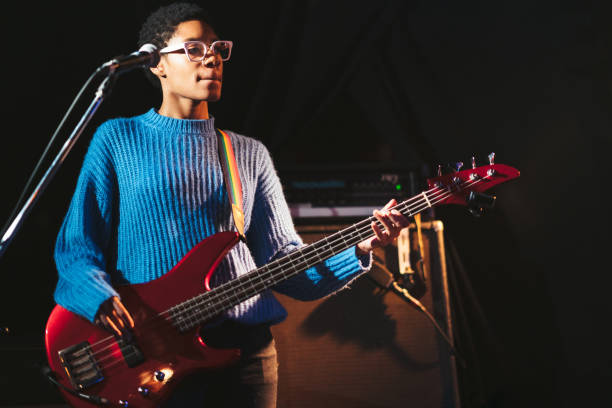 guitarra femenina negra tocando el bajo en el escenario - bass guitar fotografías e imágenes de stock