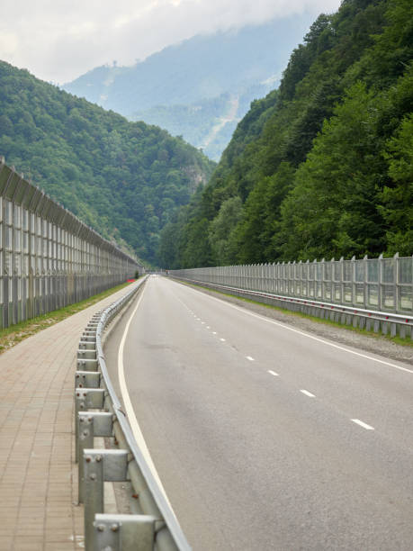 Modern road with noise insulating fences among green mountains