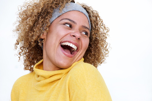 Close up portrait of beautiful african american woman laughing and turning over shoulder against isolated white background