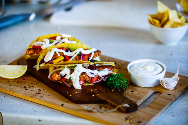 Grilled chicken meat, nachos and vegetables on wooden background