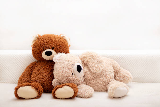 Children's toys - bears of brown and beige color are sitting on the sofa. Children's toys - bears of brown and beige color are sitting on the sofa. Selective focus. behavior teddy bear doll old stock pictures, royalty-free photos & images