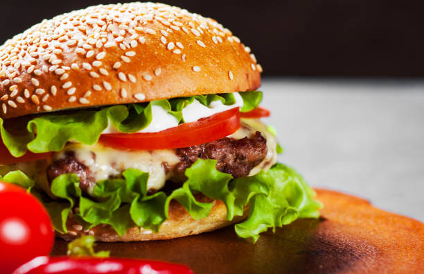 istock burger with meat, cheese and vegetables on wooden board 1137801356