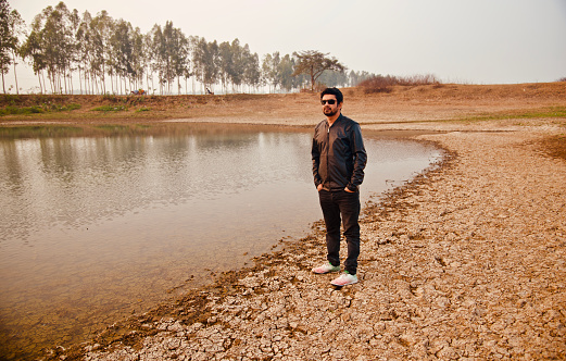 Man wearing black dress standing beside water of a lake