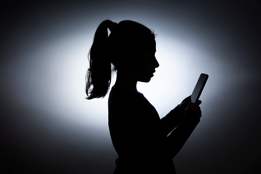 silhouette of little girl using mobile