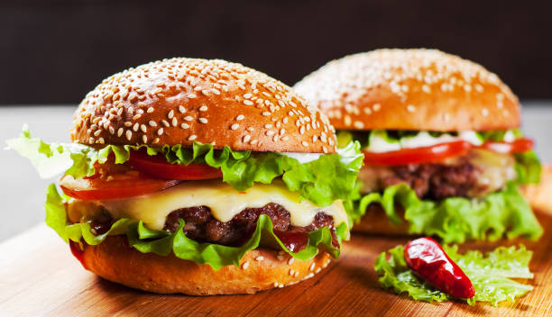 Two Burger With Meat Cheese And Vegetables On Wooden Board Stock