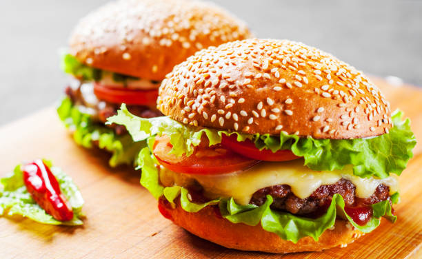 Two Burger With Meat Cheese And Vegetables On Wooden Board Stock