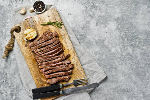 istock Sliced BBQ steak on wooden chopping Board. Gray background, top view, space for text 1137814775