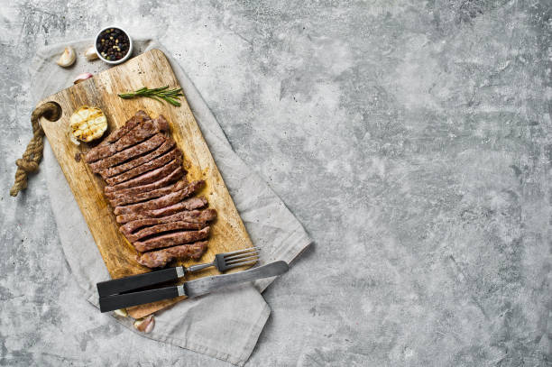 istock Sliced beef flank steak on wooden chopping Board. Gray background, top view, space for text 1137815944