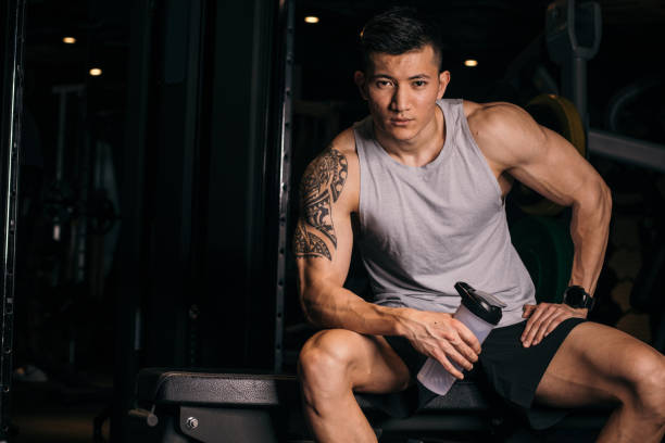 asian bodybuilder sitting on a bench - body care asian ethnicity body building toughness imagens e fotografias de stock