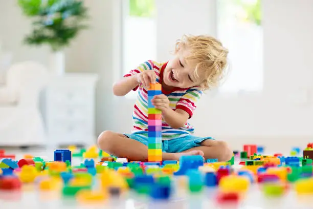 Photo of Child playing with toy blocks. Toys for kids.