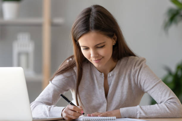 istock Focused woman writing notice, using laptop, preparing to pass exam 1137821449