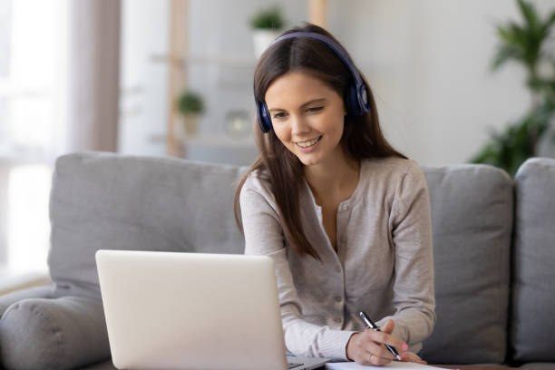 istock Smiling woman in headphones using laptop, writing notes 1137821458