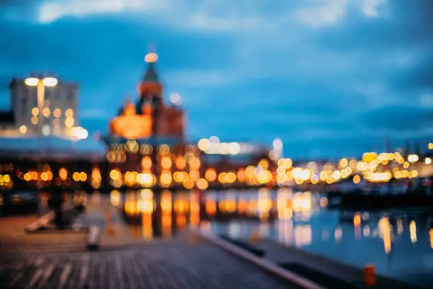 Photo of Helsinki, Finland. Abstract Blurred Bokeh Architectural Urban Background Of Uspenski Cathedral And City Embankment. Real Defocused Backdrop Lights Of City Street In Evening Night Illumination