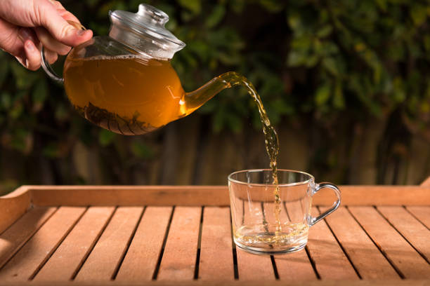 istock Pouring tea from a teapot into a cup on a blurred background of nature 1137832411