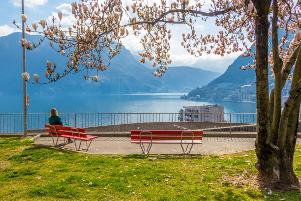 girl enjoying city view from a bench under the magnolia tree at the hill in lugano - switzerland ticino canton lake lugano imagens e fotografias de stock